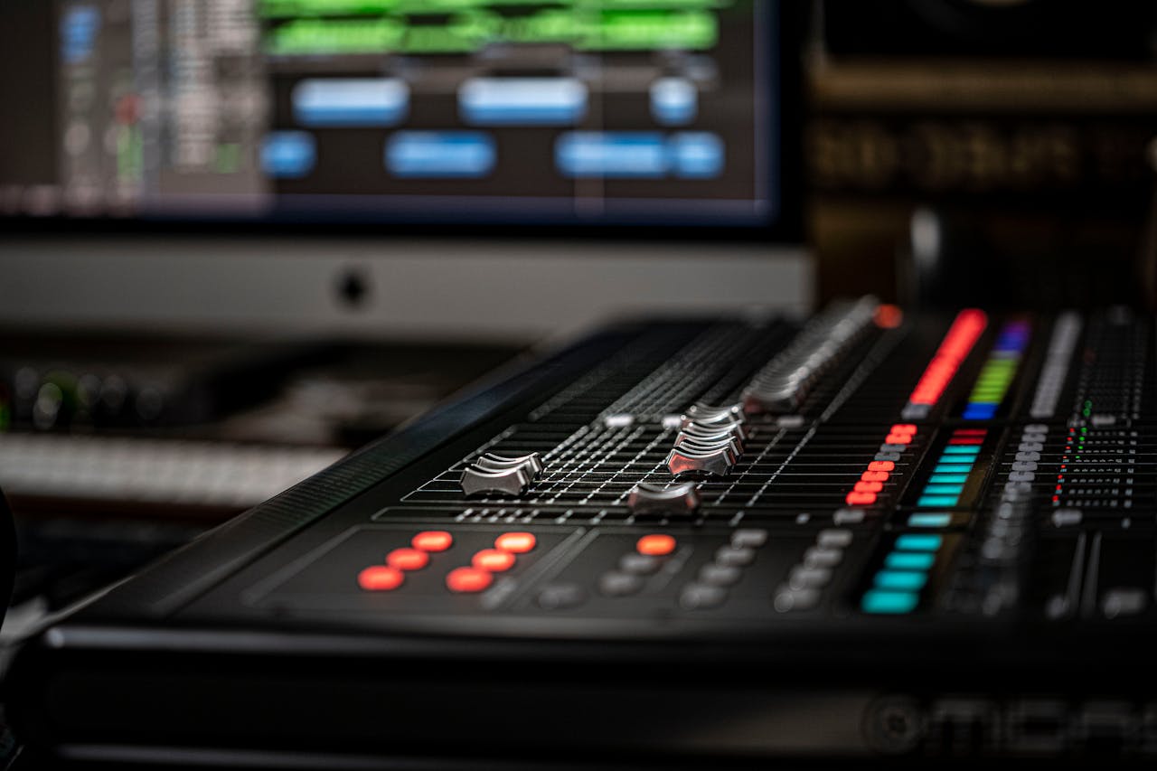 Detailed photo of an audio mixer with vibrant lights and screens in a professional studio.