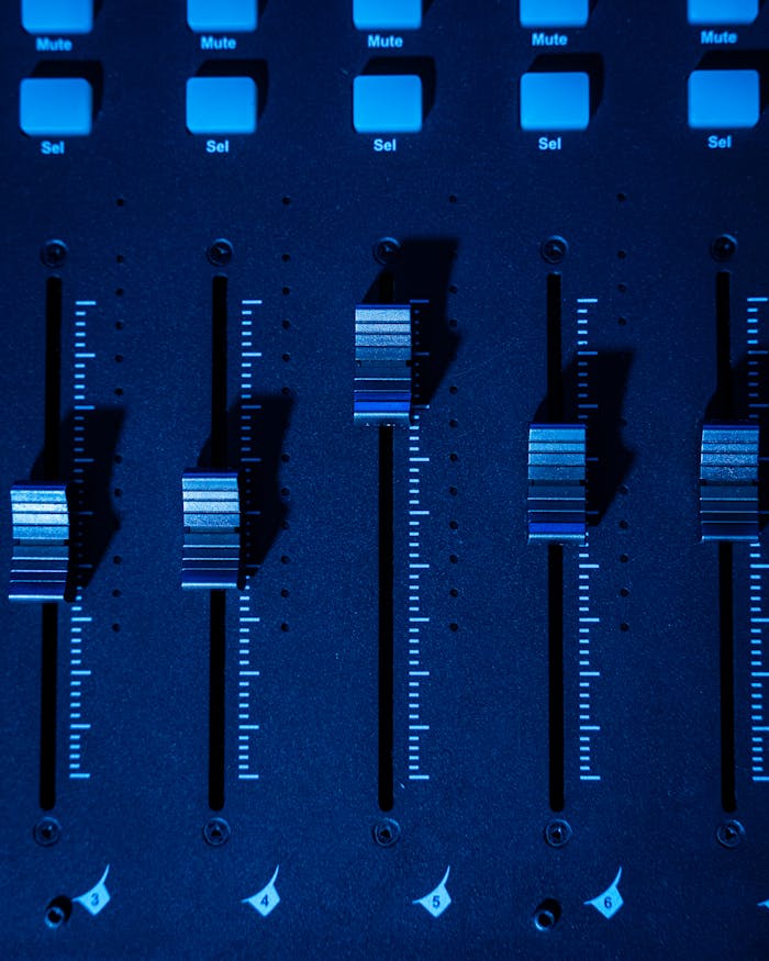 Detailed shot of a mixing console faders with blue lighting, ideal for music production themes.