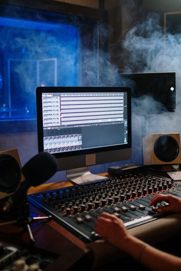 A modern music studio with audio mixer and computer screen displaying tracks.